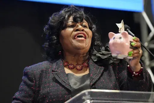 Addie Lee Green, Democratic nominee for Mississippi State Treasurer, holds a piggy bank with a $100 dollar bill stuffed in it, as she addresses the group of business leaders at the 2023 Hobnob, sponsored by the Mississippi Economic Council, in Jackson, Miss., Thursday, Oct. 26, 2023. (AP Photo/Rogelio V. Solis)