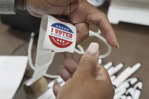 A precinct worker precuts "I Voted" stickers from a long roll prior to the site opening up for voters Tuesday, Nov. 5, 2024, in Jackson, Miss. (AP Rogelio V. Solis)