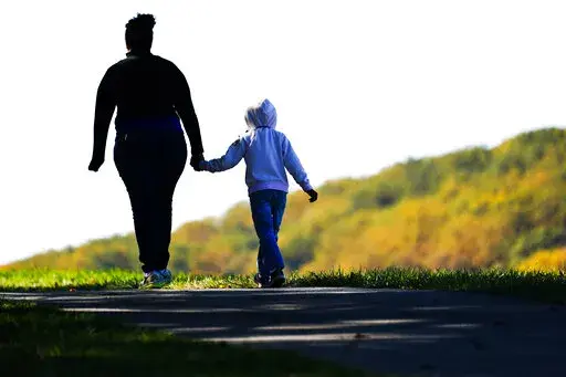 A woman and child walk on a trail at Valley Forge National Historical Park in Valley Forge, Pa., Nov. 1, 2021. Senate Democrats and Republicans each want to flash election-year signals that they’re helping families struggling with rising costs and the two-year-old pandemic. But the parties differ over how to do that. (AP Photo/Matt Rourke, File)