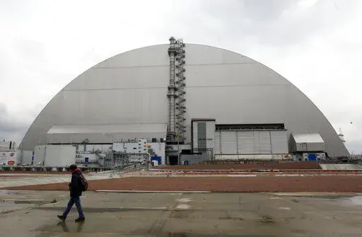A man walks past a shelter covering the exploded reactor at the Chernobyl nuclear plant, in Chernobyl, Ukraine, Thursday, April 15, 2021. When fighting from Russia’s invasion of Ukraine resulted in power cuts to the critical cooling system at the closed Chernobyl nuclear power plant, some feared that spent nuclear fuel would overheat. But nuclear experts say there’s no imminent danger because time and physics are on safety's side. (AP Photo/Efrem Lukatsky, File)