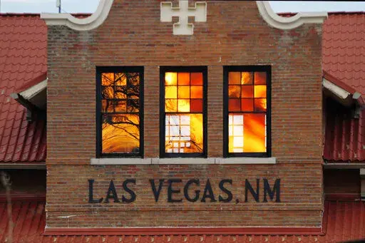 Reddened by wildfire smoke, the sun is seen reflected off windows at the train station in Las Vegas, N.M., on Saturday, May 7, 2022. Area residents have been on and off of evacuation orders of the past month as fires grow and move with intense and unpredictable winds. (AP Photo/Cedar Attanasio)