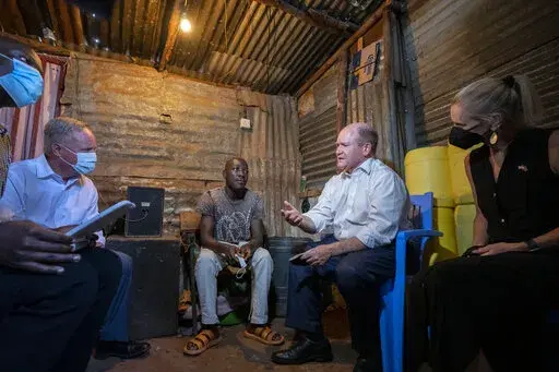 Sen. Chris Coons, second right, leading a U.S. congressional delegation, is accompanied by his wife Annie Coons, right, and Rep Dave Joyce, left, as he speaks to patient David Oduor, center, at his home, after visiting the Tabitha Medical Clinic run by CFK Africa in the Kibera neighborhood of Nairobi, Kenya Thursday, Aug. 18, 2022. The delegation also met with current President Uhuru Kenyatta, Kenya's new president-elect William Ruto, and opposition figure Raila Odinga who has said he will chall