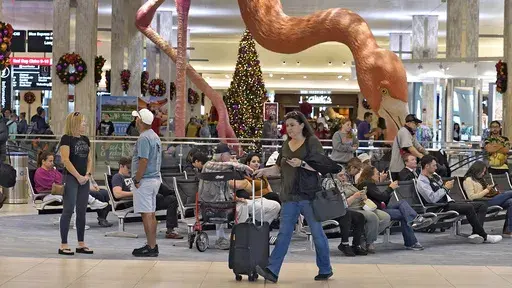 Holiday travelers pass by "Phoebe" the Flamingo at the Tampa International Airport, Friday, Dec. 22, 2023, in Tampa, Fla. Conditions were mostly nice for travelers flying ahead of and on Christmas Day this year, but some naughty disruptions plagued those flying with Southwest Airlines again this year. By midday Monday, Dec. 25, only 138 flights within, into or out of the U.S. had been canceled and 1,366 were delayed, according to FlightAware, a tracking website. (AP Photo/Chris O'Meara, File)