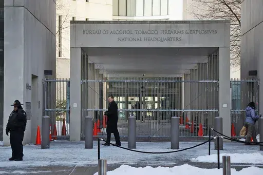 In this Thursday, Jan. 23, 2014 photo, a security official walks in front of the entrance to the national headquarters of the Bureau of Alcohol, Tobacco, Firearms and Explosives in Washington. On Friday, March 1, 2024, The Associated Press reported on stories circulating online incorrectly claiming an update to the Bureau of Alcohol, Tobacco, Firearms and Explosives’ background check policy allows people in the U.S. illegally to purchase firearms. (AP Photo/Charles Dharapak, File)