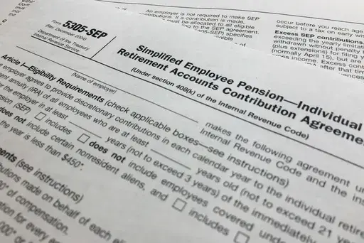 In this April 2, 2018, file photo, an IRS Form 5305, Simplified Employee Pension — Individual Retirement Accounts Contribution Agreement is shown in New York. Companies have long helped their workers save for retirement through 401(k)s and other workplace plans. But recent SECURE 2.0 legislation has blessed a newer trend: employers creating emergency savings options that could encourage workers to save more and avoid raiding their retirement funds. (AP Photo/Jenny Kane, File)