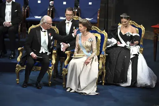 Sweden's King Carl Gustaf adjusts a pillow for Queen Silvia at the Nobel award ceremony at Stockholm Concert Hall, in Stockholm, on Tuesday Dec. 10, 2019. (Claudio Bresciani / TT Pool via AP, File)