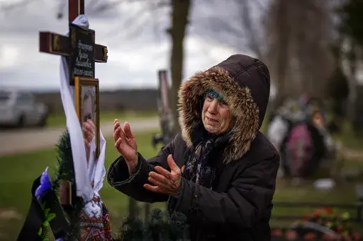 Valentyna Nechyporenko, 77, mourns at the grave of her 47-year-old son Ruslan, during his funeral at the cemetery in Bucha, on the outskirts of Kyiv, Monday, April 18, 2022. Ruslan was killed by Russian army on March 17 while delivering humanitarian aid to his neighbours in the streets of Bucha. (AP Photo/Emilio Morenatti)