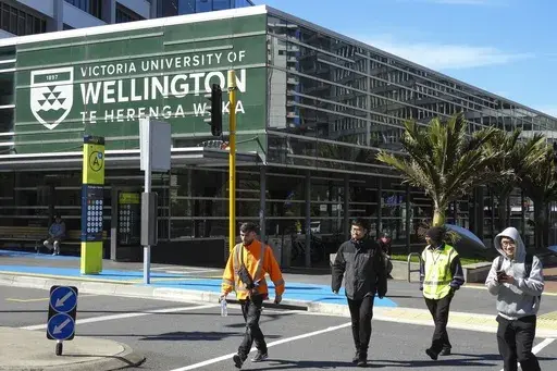 People walk past the name of Victoria University of Wellington, written in English and Maori languages as New Zealand celebrates its annual Maori language week in Wellington, New Zealand, Wednesday, Sept. 18, 2024. (AP Photo/Charlotte GrahamMcLay)