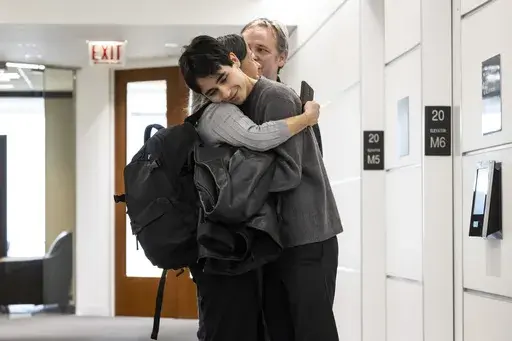 Lucia Morales hugs her 19-year-old son, Rylan Wilder in the hallway at their attorney's office in the Loop, Wednesday, Oct. 18, 2023. Wilder, who was shot and wounded during a 2019 shootout between suburban Chicago police and a bank robbery suspect inside a music school has reached a $1.9 million settlement with the city of Des Plaines. (Ashlee Rezin /Chicago Sun-Times via AP)