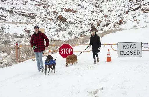 Parker Smith and Hillary Smith hike along a closed road outside Arches National Park in Utah which is closed due to the partial government shutdown, in January 2019. Arizona's Grand Canyon National Park and all five national parks in Utah will remain open if the U.S. government shuts down, Sunday, Oct. 1, 2023. Arizona Gov. Katie Hobbs and Utah Gov. Spencer Cox say that the parks are important destinations and local communities depend on dollars from visitors. (Rick Egan/The Salt Lake Tribune vi
