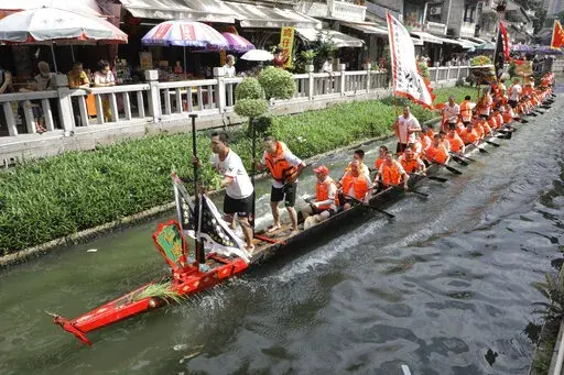Dragon boat participants from Panting village row along a canal in the historic Lychee Bay scenic area in Guangzhou in southern China's Guangdong Province, Friday, June 3, 2022. Dragon boat races returned in parts of China on Friday for the first time since the outbreak of the pandemic in late 2019, as restrictions are lifted along with a major drop in COVID-19 cases. (AP Photo/Caroline Chen)