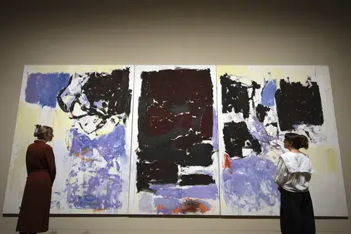 Museum employees view a painting by artist Joan Mitchell called Iva 1973, donated by Jorge M. and Darlene Perez, at the Tate Modern in London, Thursday, April 3, 2025. (AP Photo/Kirsty Wigglesworth)