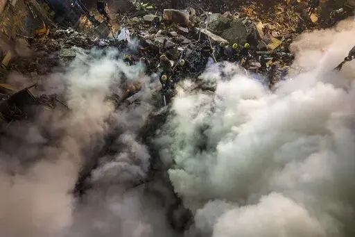 Emergency workers clear the rubble after a Russian rocket hit a multistory building leaving many people under debris in the southeastern city of Dnipro, Ukraine, Saturday, Jan. 14, 2023. (AP Photo/Evgeniy Maloletka)