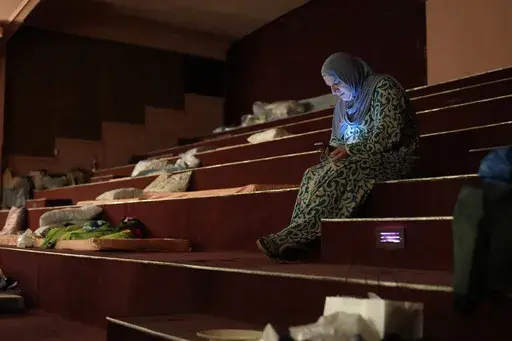 Mona Hanafi, a Lebanese displaced woman who fled the ongoing Hezbollah-Israel war in south Lebanon, looks at her mobile phone inside one of Beirut's oldest and best known movie theatres, Le Colisee, where she is sheltering with her family, in Beirut, Lebanon, Tuesday, Oct. 22, 2024. (AP Photo/Hussein Malla)