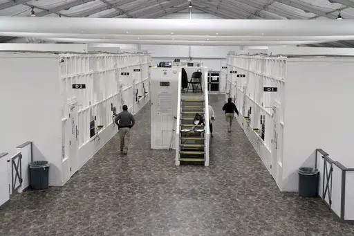 Agents walk among rooms at a Border Patrol holding facility on Dec. 15, 2023, in Tucson, Ariz. U.S. asylum officers were instructed nearly a year ago to apply a higher screening standard on people who cross the border illegally to claim asylum after passing through another country. But they are too understaffed to have much impact. (AP Photo/Gregory Bull, File)