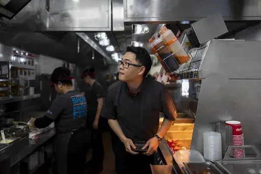 Lawrence Cheng, whose family owns seven Wendy's locations south of Los Angeles, works in the kitchen at his Wendy's restaurant in Fountain Valley, Calif., June 20, 2024. Cheng used to have nearly a dozen employees at his Fountain Valley location during the day. Now, he only schedules seven for each shift as he scrambles to absorb a dramatic jump in labor costs after a new California law boosted the hourly wage for fast food workers on April 1 from $16 to $20 an hour. (AP Photo/Jae C. Hong)
