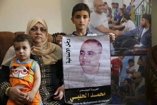 Amal el-Halabi holds her grandson Fares while her grandson Amro, 7, holds a picture of his father Mohammed el-Halabi, Gaza director of the international charity World Vision, who is detained and accused by Israeli security of diverting sums to Hamas that exceed its total budget, at his family house in Gaza City, Aug. 8, 2016. In May 2022, nearly six years after Israel accused Mohammed el-Halabi of diverting tens of millions of dollars from an international charity to Gaza's militant Hamas rulers