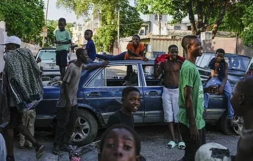 Youths hang out near cars serving as street barricades placed there by residents to deter gangs from entering their neighborhood, in downtown Port-au-Prince, Haiti, May 17, 2024. (AP Photo/Ramon Espinosa, File)