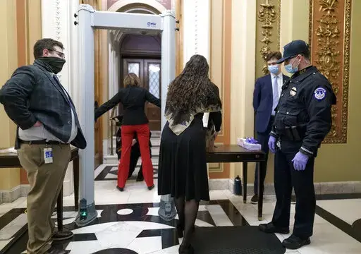 Congressional staff passes through a metal detector and security screening as they enter the House chamber, new measures put into place after a violent mob loyal to President Donald Trump stormed the Capitol, in Washington, Jan. 12, 2021. (AP Photo/J. Scott Applewhite, File)