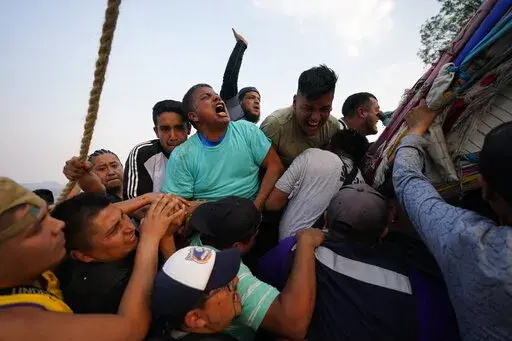 People work to lower a heavy, wooden cross from a hilltop to carry it to a church as part of celebrations marking the day of the Holy Cross, in the Santa Cruz Xochitpec neighborhood of Mexico City, late Monday, May 2, 2022. The importance of the fabric-draped cross is reflected in the town's very name, which means "Holy Cross of the Flowered Hill." (AP Photo/Eduardo Verdugo)