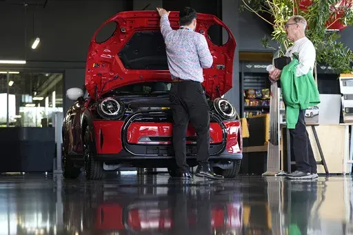 A salesperson shows an unsold 2024 Cooper SE electric hardtop to a prospective buyer in the showroom of a Mini dealership Wednesday, May 1, 2024, in Highlands Ranch, Colo. (AP Photo/David Zalubowski, File)