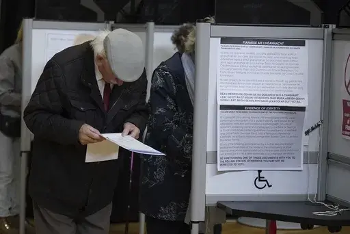 A man looks at the ballot papers before casting his vote in the local and European elections at the Deaf Village in Dublin, Ireland, Friday June 7, 2024. (Niall Carson/PA via AP)