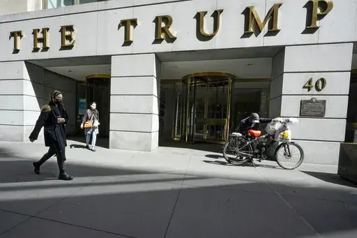 Pedestrians and a food delivery man are seen outside the Trump building on Wall Street, in New York's Financial District, March 23, 2021. (AP Photo/Mary Altaffer, File )