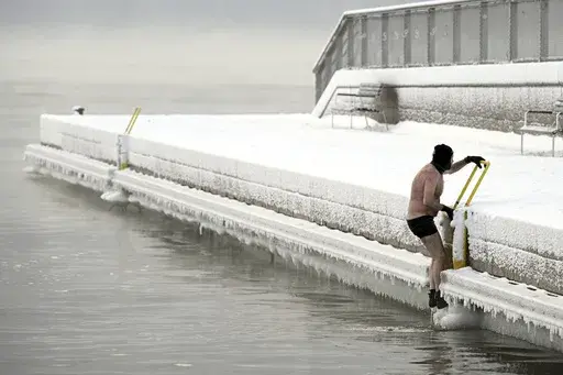 A man climbs out from the icy sea to the pier, in southern Helsinki, Finland, Tuesday, Jan. 2, 2024. Finland and Sweden have recorded this winter’s cold records on Tuesday as a temperatures plummeted to over minus 40 degrees as a result of a cold spell prevailing in the Nordic region. (Vesa Moilanen/Lehtikuva via AP)