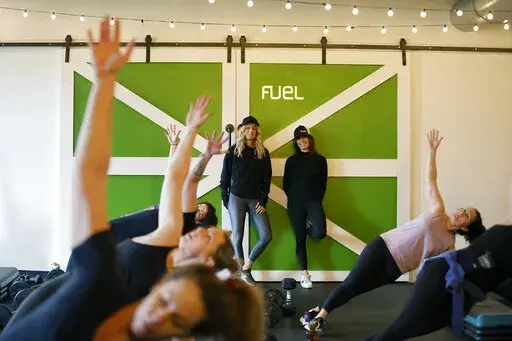 Fuel Training Studio owners Julie Bokat, left, and Jeanne Carter watch a fitness class inside their gym, Thursday, Jan. 19, 2023, in Newburyport, Mass. Gyms and fitness studios were among the hardest hit businesses during the pandemic. But for gyms who made it through the worst, signs of stability are afoot. (AP Photo/Mary Schwalm)