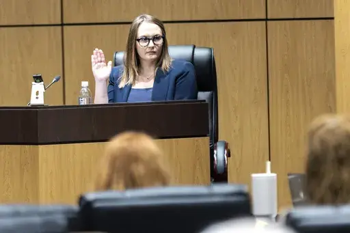 Cobb County teacher Katie Rinderle is sworn in to testify during a hearing at the Cobb County Board of Education in Marietta, Ga., Aug. 10, 2023. The firing of Rinderle, a Georgia teacher who read a book on gender fluidity to her fifth grade class, was upheld Thursday, Feb. 22, 2024, by the Georgia Board of Education. (Arvin Temkar/Atlanta Journal-Constitution via AP, File)