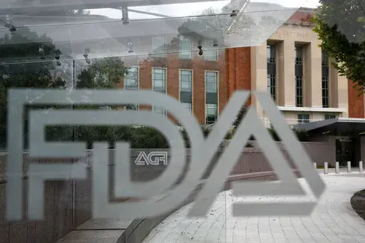 This Aug. 2, 2018 file photo shows the U.S. Food and Drug Administration building behind FDA logos at a bus stop on the agency's campus in Silver Spring, Md. The Food and Drug Administration has issued a negative review of a closely watched experimental drug for the debilitating illness known as Lou Gehrig’s disease. The review comes ahead of a meeting this week for outside experts to vote on the drug for ALS. The drug has been the focal point of a lobbying campaign by patients, their families