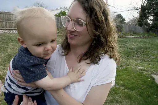 Sarah Perkins holds her 1-year-old son, Cal Sabey, at a relative's home in Centennial, Colo., Wednesday, May 3, 2023. Perkins and her husband are suing police and social workers in Massachusetts after their two young children were taken by the state's Department of Children and Families in July 2022. Hospital staff discovered that Cal had suffered a broken rib and flagged the couple for possible child abuse. The couple's lawsuit alleges constitutional violations including the unreasonable search