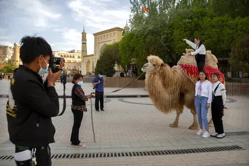Tourists pose for photos with a camel outside the Id Kah Mosque in Kashgar in western China's Xinjiang Uyghur Autonomous Region, as seen during a government organized trip for foreign journalists, on April 19, 2021. After a U.N. report concluding that China's crackdown in the far west Xinjiang region may constitute crimes against humanity, China used a well-worn tactic to deflect criticism: blame a Western conspiracy. (AP Photo/Mark Schiefelbein, File)