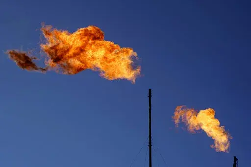 Flares burn off methane and other hydrocarbons at an oil and gas facility in Lenorah, Texas, Friday, Oct. 15, 2021. Climate scientists have found that methane emissions from the oil and gas industry are far worse than what companies are reporting, despite claims by some major firms that they’ve reduced their emissions. (AP Photo/David Goldman, File)