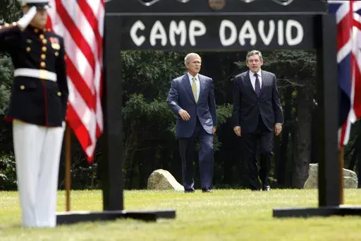 President George W. Bush, left, and British Prime Minister Gordon Brown walk to a joint press availability at Camp David, Md., July 30, 2007. (AP Photo/Charles Dharapak, File)
