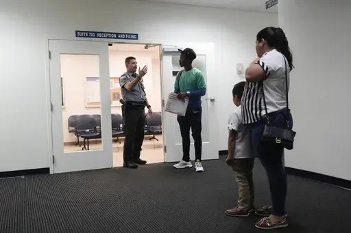An officer directs people to a courtroom, Jan. 10, 2024, in an immigration court in Miami. A 53-year-old union of immigration judges has been ordered to get supervisor approval to speak publicly to anyone outside the Justice Department, potentially quieting a frequent critic of heavily backlogged immigration courts in an election year. (AP Photo/Wilfredo Lee, File)