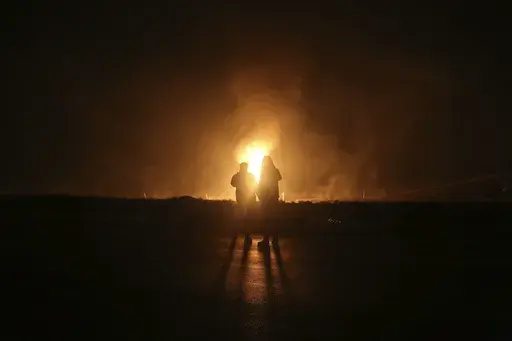 Two men look at flames after a natural gas pipeline explodes outside the city of Boroujen in the western Chaharmahal and Bakhtiari province, Iran, in early Wednesday, Feb. 14, 2024. Explosions struck a natural gas pipeline in Iran early Wednesday, with an official blaming the blasts on a "sabotage and terrorist action" in the country as tensions remain high in the Middle East amid Israel's war on Hamas in the Gaza Strip. (Reza Kamali Dehkordi/Fars News Agency via AP)