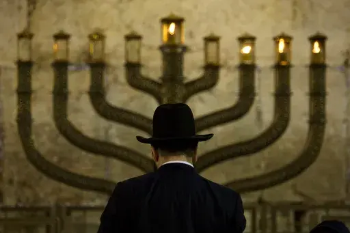 An Ultra-Orthodox Jewish man stands in front of a menorah on the third eve of Hanukkah, at the Western Wall, Judaism's holiest site in Jerusalem's old city, Sunday, Dec. 13, 2009. On eight consecutive nightfalls, Jews gather with family and friends to light one additional candle in the menorah candelabra. They do so to commemorate the rededication of the Temple in Jerusalem in the 2nd century BC, after a small group of Jewish fighters liberated it from occupying foreign forces. (AP Photo/Sebasti