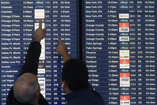 Two men point toward plane arrivals on a flight information board at San Francisco International Airport in San Francisco, Tuesday, Nov. 26, 2019.   Forecasters say, Friday, March 11, 2022,  a powerful, late-winter storm combining rivers of moisture and frigid temperatures is expected to dump snow from the Deep South all the way north to the Canadian border over the weekend that could cause travel problems and power outages across a wide part of the Eastern United States from late Friday through