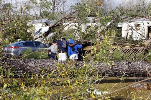 Friends and family pray outside a damaged mobile home, Wednesday, Nov. 30, 2022, in Flatwood, Ala., the day after a severe storm swept through the area. Two people were killed in the Flatwood community just north of the city of Montgomery. (AP Photo/Butch Dill)