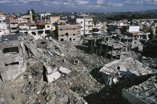 A man stands next to destroyed buildings after returning to the village of Qana, southern Lebanon, Thursday, Nov. 28, 2024 following a ceasefire between Israel and Hezbollah that went into effect on Wednesday.(AP Photo/Hussein Malla)