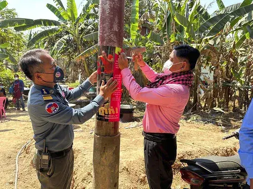 In this photo released by the Cambodia Ministry of Health, a Cambodia animal health officer, right, and a military police officer place posters about awareness of H5N1 virus threats in hopes of educating villagers to take care of their health, in Prey Veng eastern province Cambodia, Thursday, Feb. 23, 2023. An 11-year-old girl in Cambodia has died from bird flu in the country's first known human H5N1 infection since 2014, health officials said. (Cambodia Ministry of Health via AP)