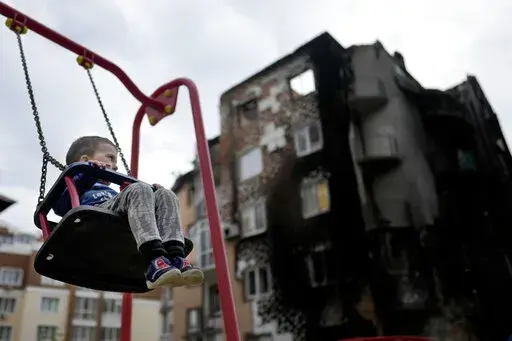 Yarik sits in a swing at a playground outside a building destroyed during attacks in Irpin, Ukraine, on the outskirts of Kyiv, on Monday, May 30, 2022. (AP Photo/Natacha Pisarenko)