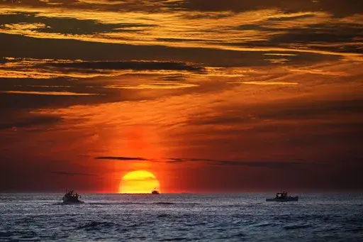 The sun rises over fishing boats in the Atlantic Ocean, Sept. 8, 2022, off of Kennebunkport, Maine. The United Nations body that regulates the world’s ocean floor is preparing to resume negotiations in July 2023, that could open the international seabed for mining, including for materials vital for the green energy transition. (AP Photo/Robert F. Bukaty, File)