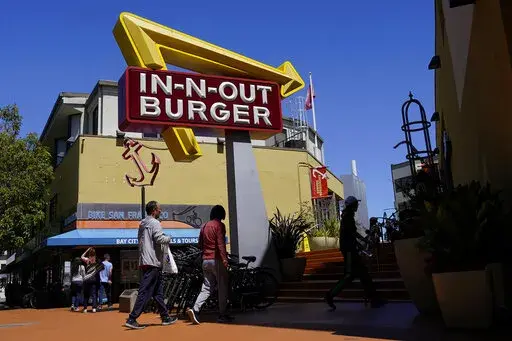 People walk below an In-N-Out Burger restaurant sign in San Francisco, Thursday, Aug. 25, 2022. The nation's employers kept hiring briskly in November despite high inflation and a slow-growing economy. Much of the growth came in education and health care, and a category made up mostly of restaurants, hotels, and entertainment firms. (AP Photo/Jeff Chiu, File)