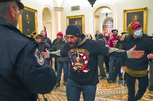 In this Jan. 6, 2021, photo, Trump supporters, including Douglas Jensen, center, confront U.S. Capitol Police in the hallway outside of the Senate chamber at the Capitol in Washington. The Iowa construction worker and QAnon follower was sentenced Friday, Dec. 16, 2022, to five years in prison for his role in the Jan. 6, 2021, insurrection at the U.S. Capitol, when he led a crowd chasing a police officer who diverted rioters away from lawmakers. (AP Photo/Manuel Balce Ceneta, File)