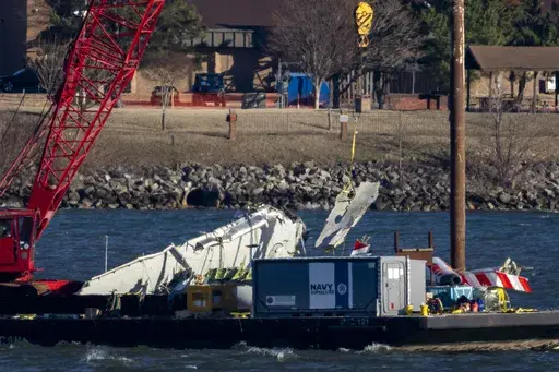 A piece of wreckage is lifted from the water onto a salvage vessel, near the site in the Potomac River of a mid-air collision between an American Airlines jet and a Black Hawk helicopter, at Ronald Reagan Washington National Airport, Tuesday, Feb. 4, 2025, in Arlington, Va. (AP Photo/Ben Curtis)