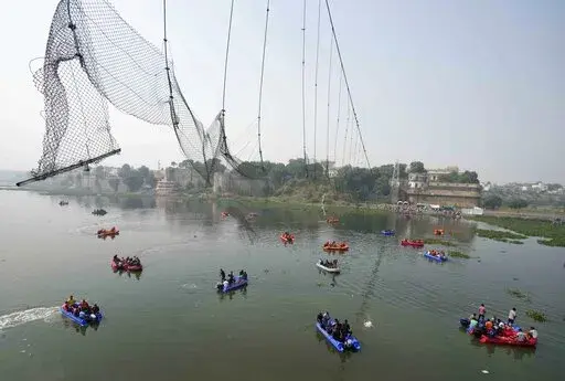 Rescuers on boats search in the Machchu river next to a cable bridge that collapsed on Sunday in Morbi town of western state Gujarat, India, Tuesday, Nov. 1, 2022. A century-old cable suspension bridge collapsed into the river Sunday evening, sending hundreds plunging in the water in one of the country's worst accidents in years. (AP Photo/Ajit Solanki)