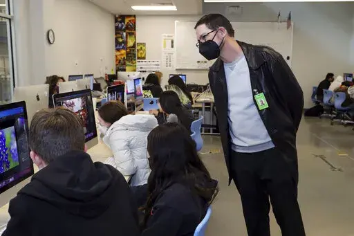 In this photo provided by the Hays Consolidated Independent School District, Brian McKinney, right, who has children in the Hays Consolidated Independent School District, in Kyle, Texas, teaches a class at Johnson High School, in Buda, Texas, Thursday, Jan. 27, 2022. McKinney, a small business owner and former teacher, is among parents the district has hired to work as substitute teachers during a staffing crunch. He returned to the classroom after about 15 years away. (Moses Leos III/Hays Conso