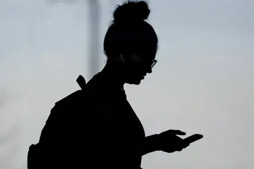 A woman checks her phone in Orem, Utah, on Nov. 14, 2019. A survey of people ages 16 to 40 finds that millennials and Generation Z follow the news, but they aren't that happy with what they're seeing. The study conducted by The Associated Press-NORC Center for Public Affairs Research and the American Press Institute says 79% of people follow news daily, contrary to perceptions that many are tuned out. (AP Photo/Rick Bowmer, File)